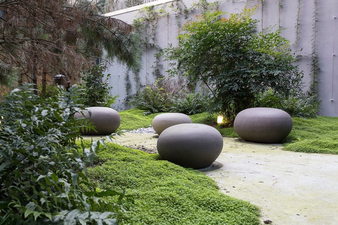 Crédit Agricole: A shaded garden patio with round stone seats on a lawn