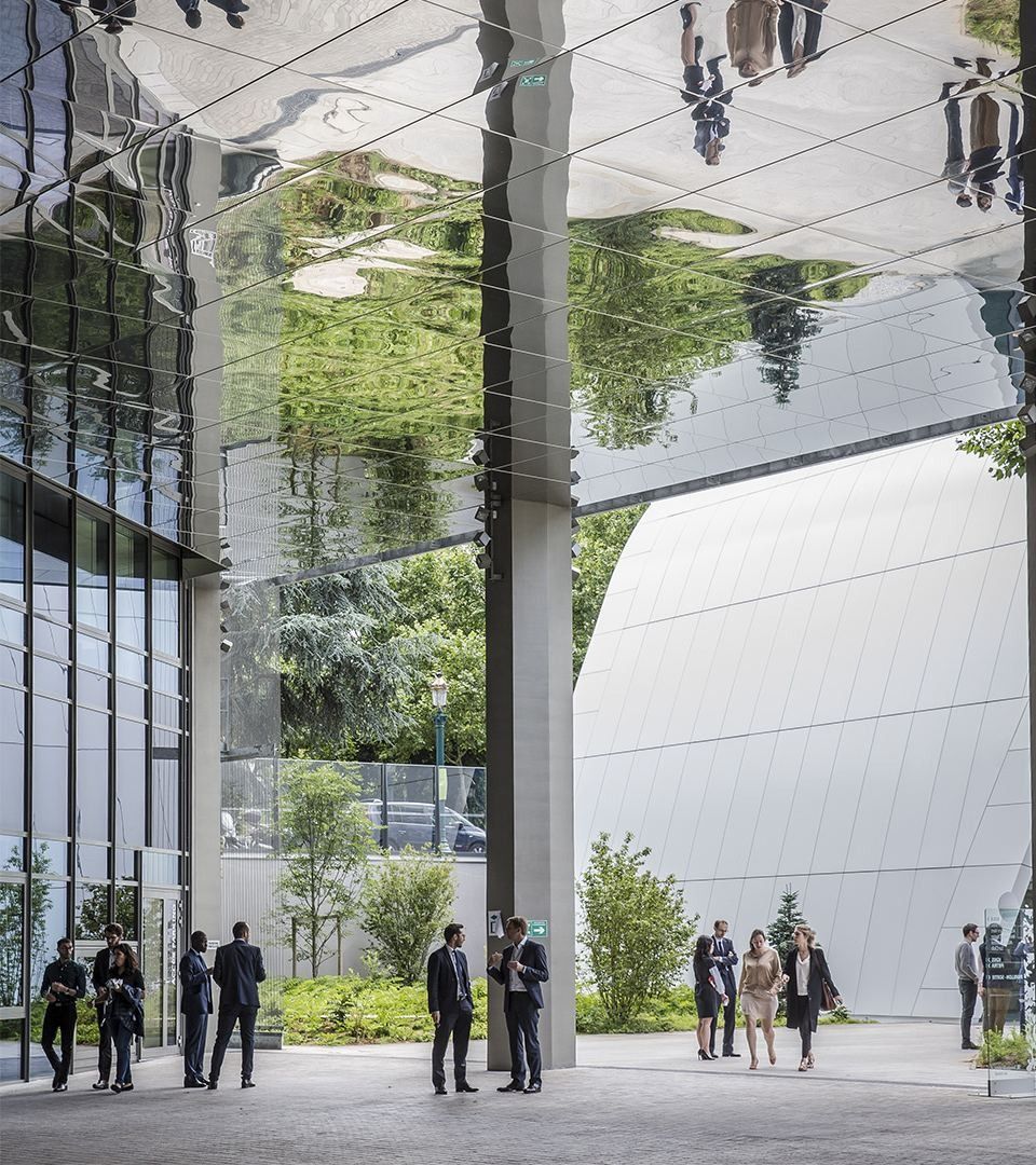Crédit Agricole: A tall glazed atrium with hanging plants and a curved white wall, with small figures on the floor