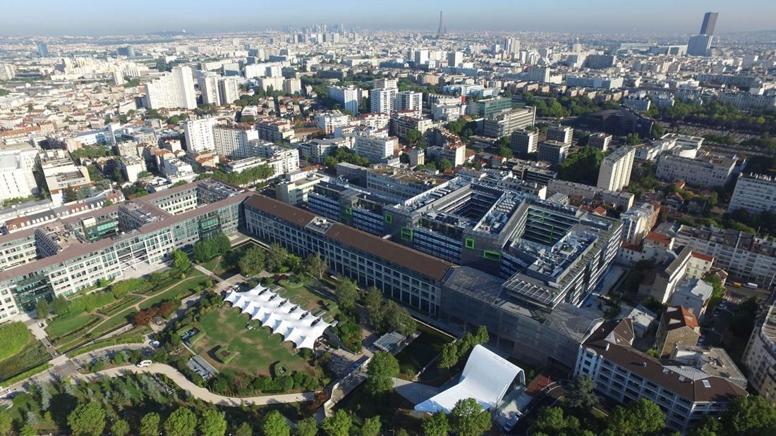 Crédit Agricole: Aerial view of low office buildings around a green park, with Paris beyond