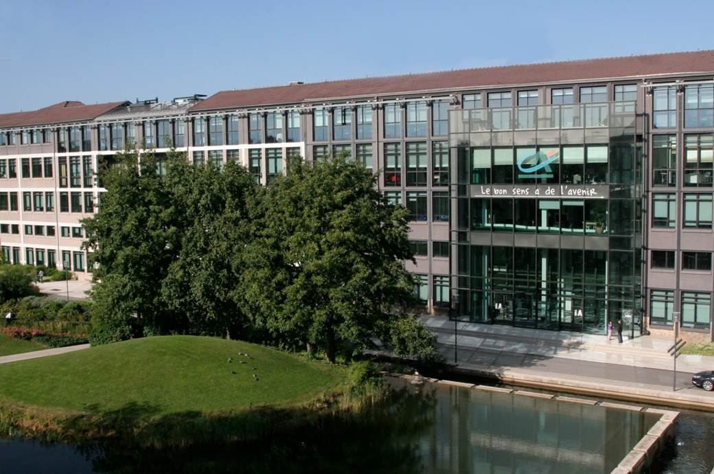 Crédit Agricole: An office building with a glazed entrance behind a lawn and a pond