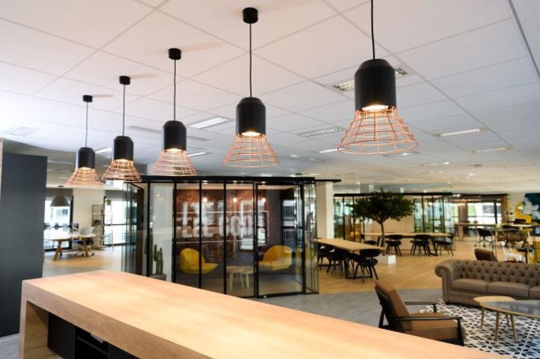Crédit Agricole: An open office floor with pendant lamps, a long wooden counter and glazed meeting rooms