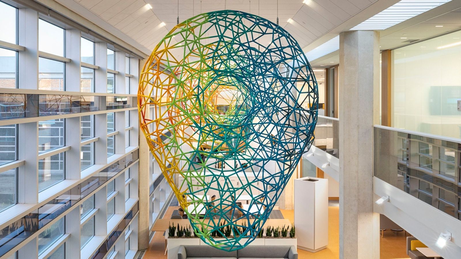 Large wire sculpture of a head hanging in a bright atrium