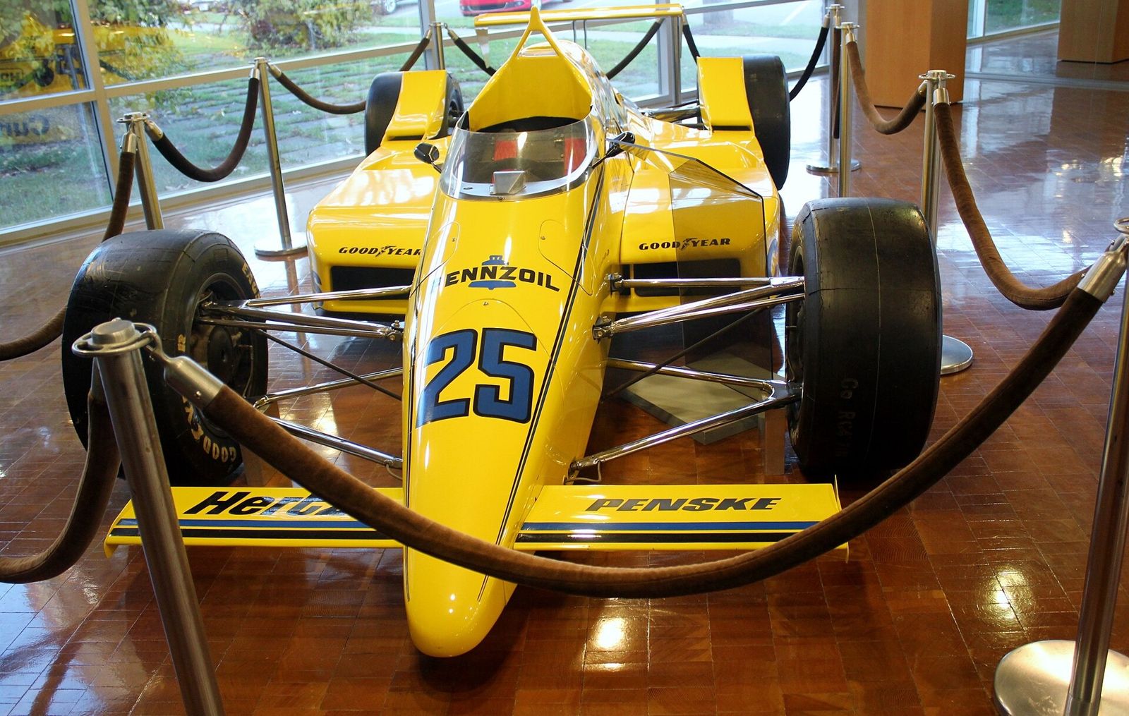 Cummins: Yellow Indy-style race car behind ropes
