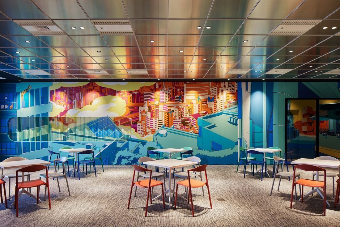 Cybozu: Café tables and orange chairs in front of a large colourful mural of a city