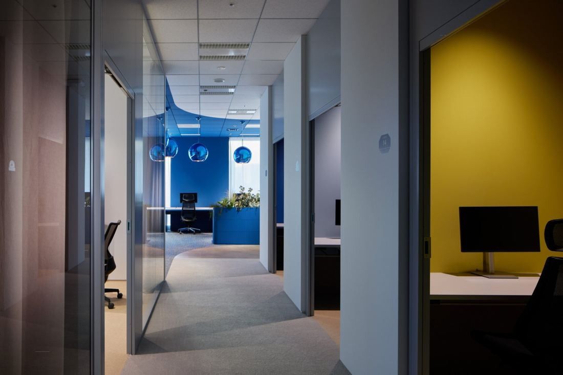 Cybozu: Corridor of small enclosed rooms with a desk and monitor and a yellow wall