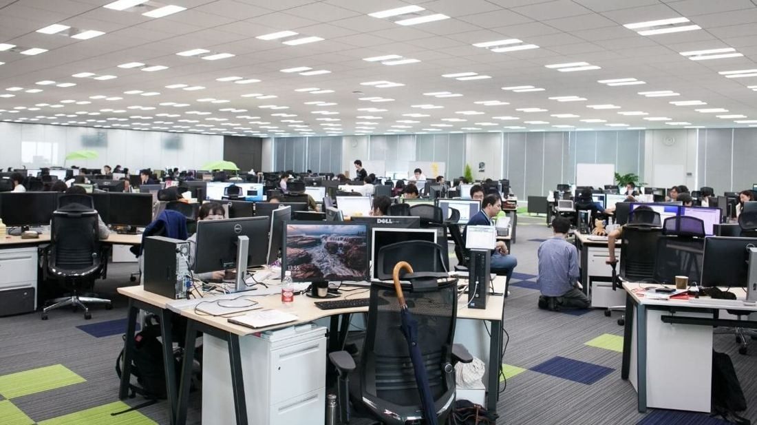 Cybozu: Large open office with rows of desks, monitors and office chairs