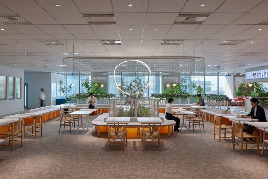 Cybozu: Open area with long white tables around planters and a large glass ring overhead