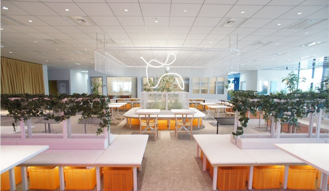 Cybozu: Rows of white tables with orange storage below and planters on the dividers