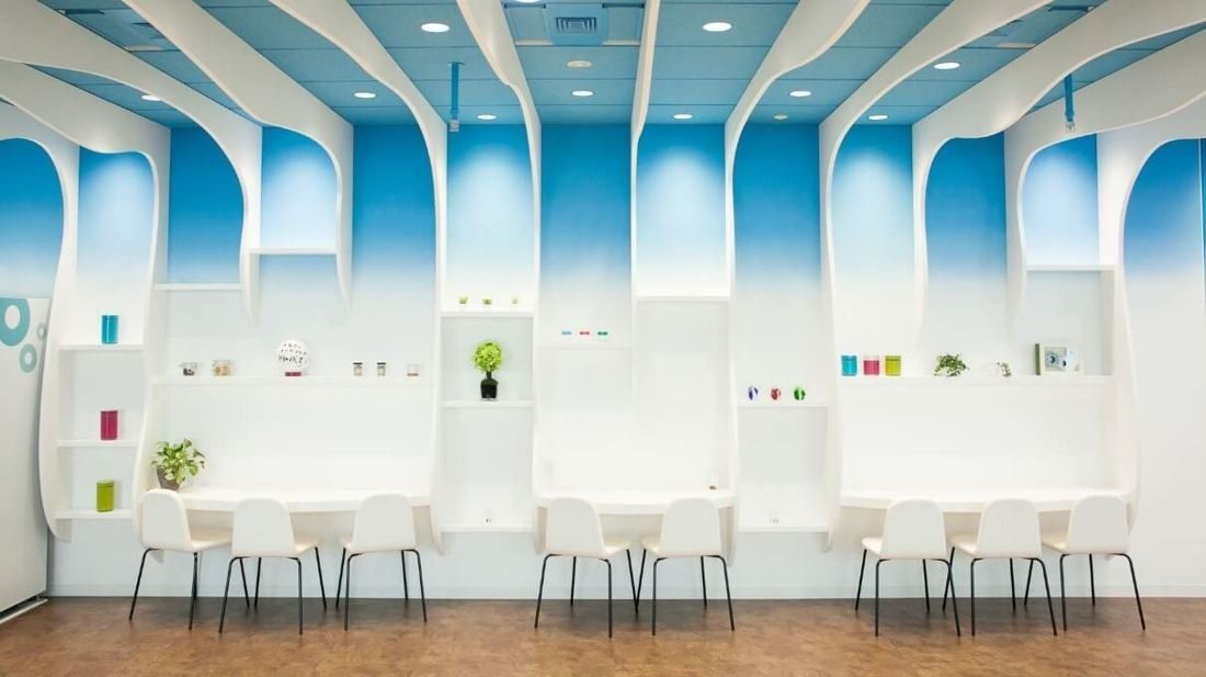 Cybozu: White wall seats under arched blue-tinted panels with small shelves