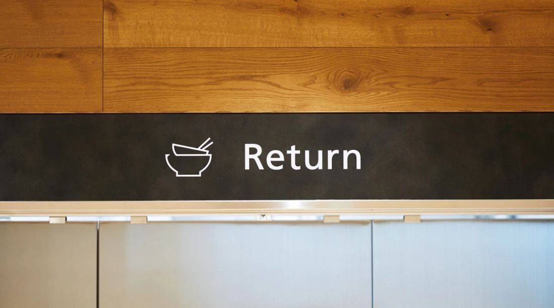 Daikin: Black band with a bowl pictogram and the word Return set into a wood-panelled wall