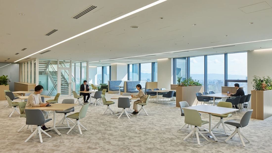 Daikin: Bright open work area with light green chairs, small tables and floor-to-ceiling windows overlooking the city