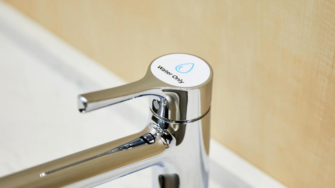 Daikin: Chrome tap with a small round label next to a light wood panel