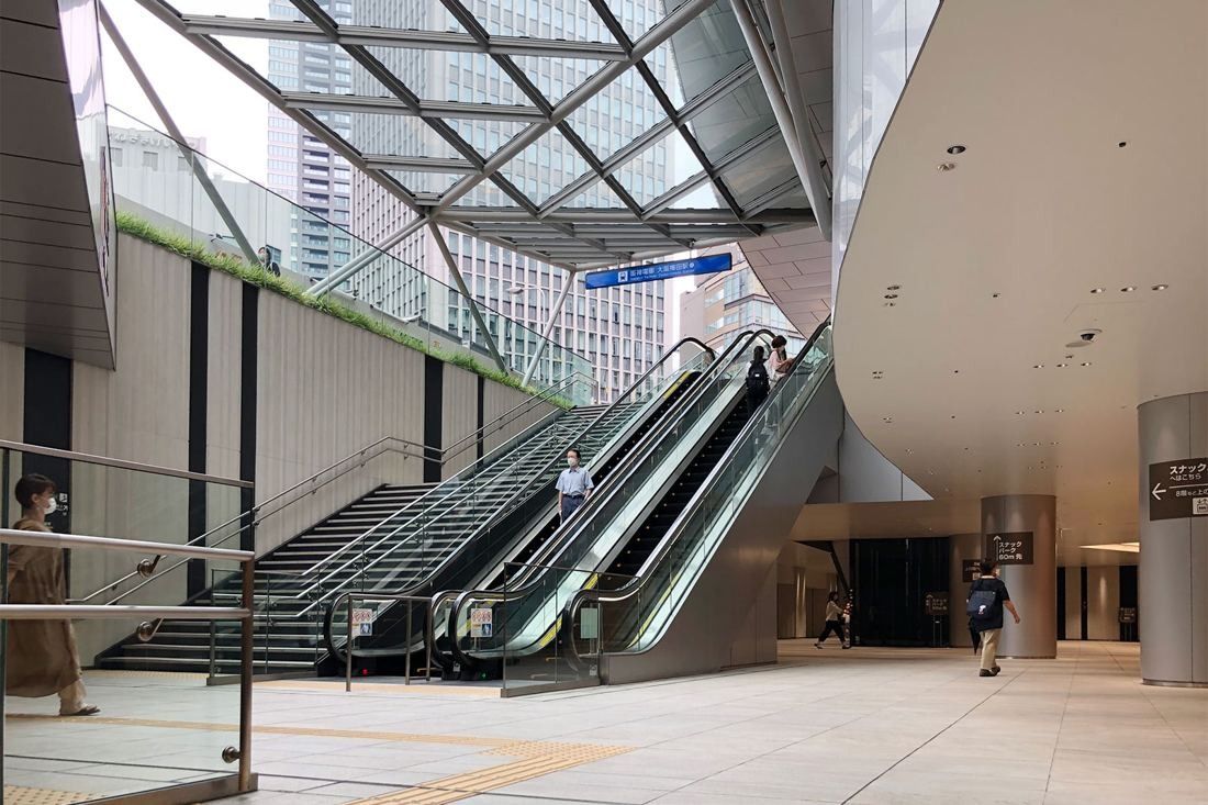 Daikin: Escalators and stairs under a diagonal glass canopy leading up from a wide covered plaza