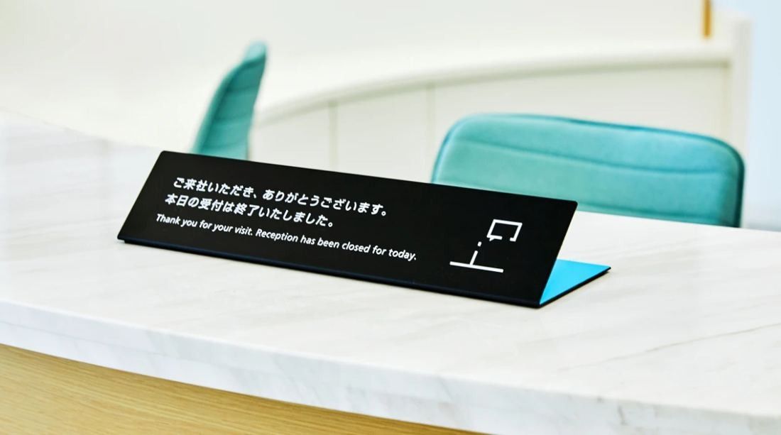 Daikin: Small black sign standing on a white marble counter in front of teal chairs