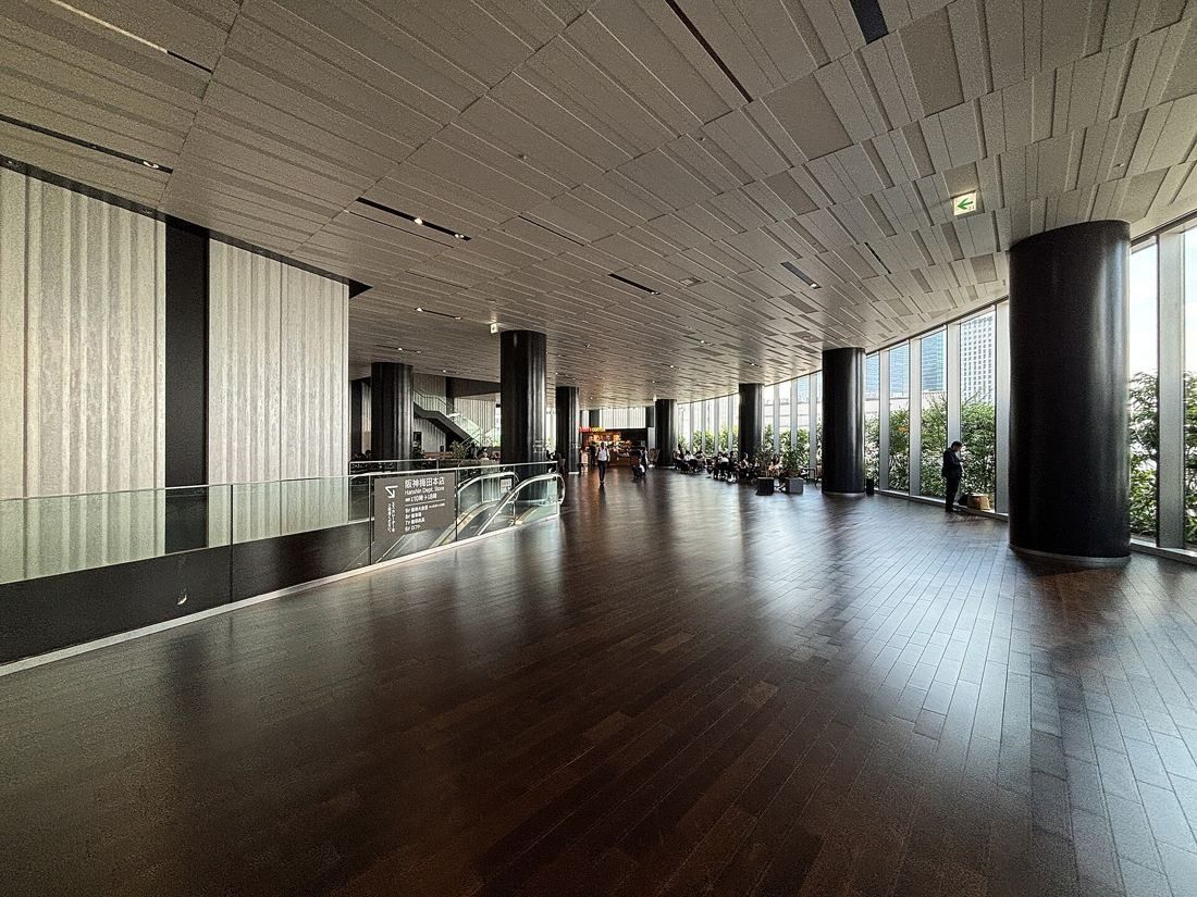 Daikin: Wide lobby with a dark wood floor, a slatted ceiling, black columns and tall windows