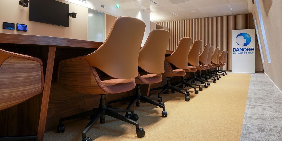 Danone: Close view of curved terracotta chairs along a long wooden table