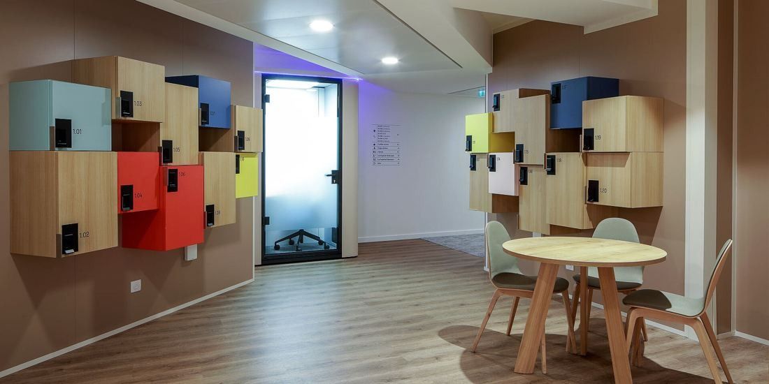 Danone: Colourful wall lockers in red, yellow and blue beside a round table and wood flooring