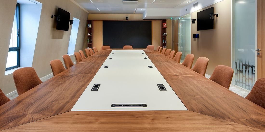 Danone: Conference table running toward a dark wall screen, with timber wall panels