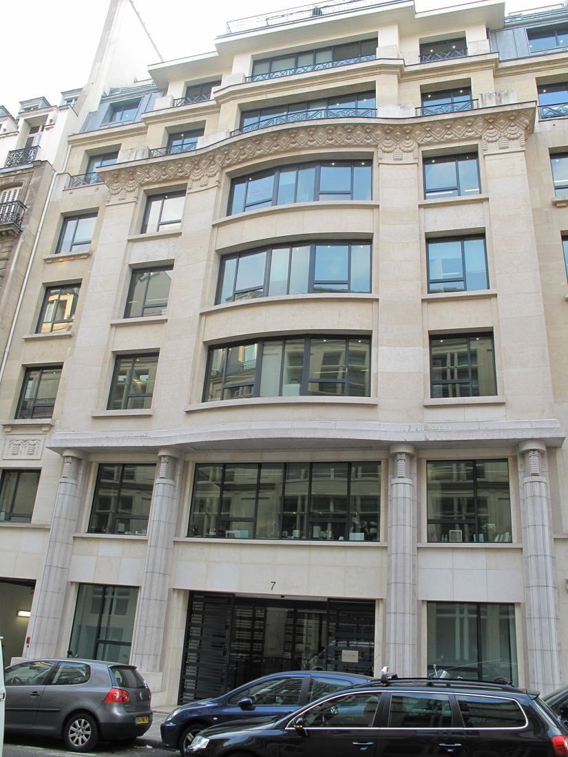 Stone apartment building with wrought-iron balconies on a Paris street
