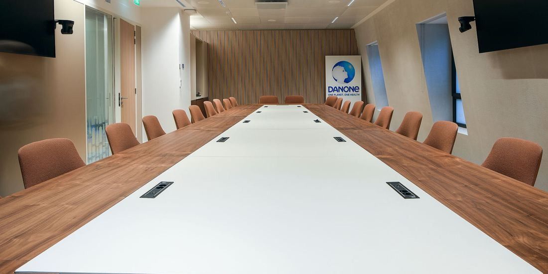 Danone: Very long white-and-wood conference table with chairs on both sides and screens on the walls