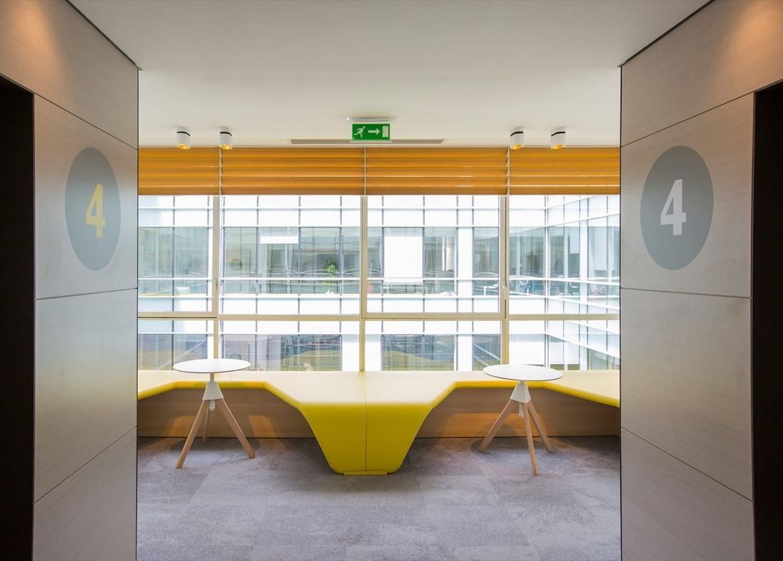 Danone: Yellow curved bench and stools facing a glazed wall, framed by grey panels marked 4