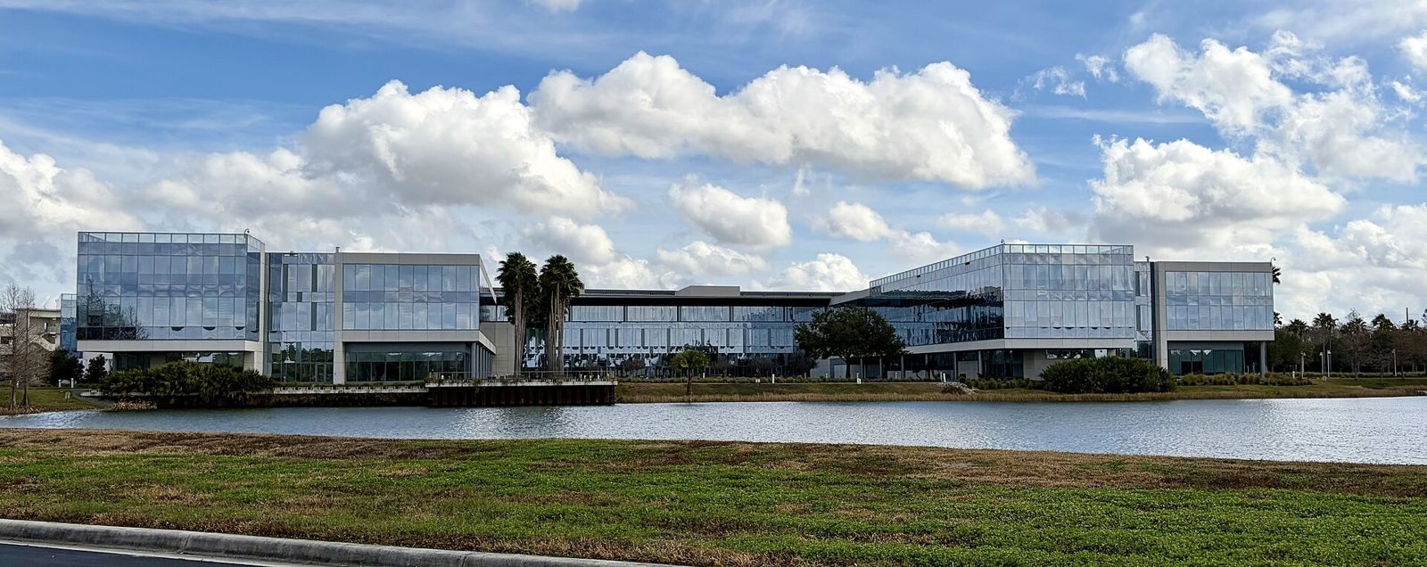 Darden Restaurants: A long glass building reflected in a lake under a blue sky