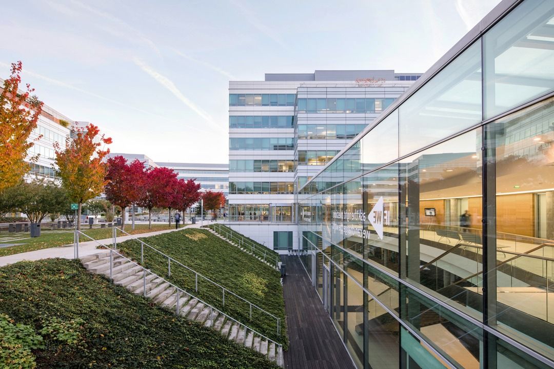 Dassault Systèmes: Glass gallery beside a sloping green roof and autumn trees