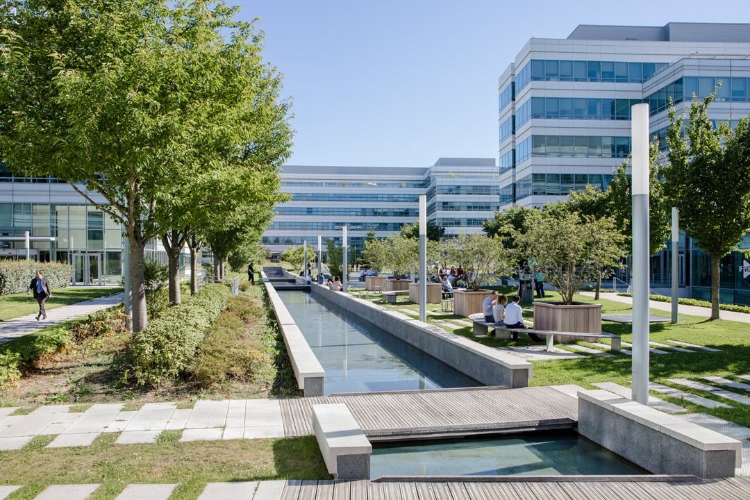 Dassault Systèmes: Long water channel between trees and glass office buildings