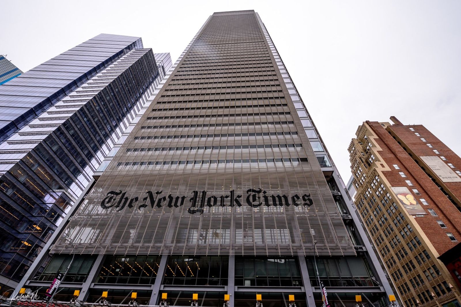 Glass tower with The New York Times sign seen from street level