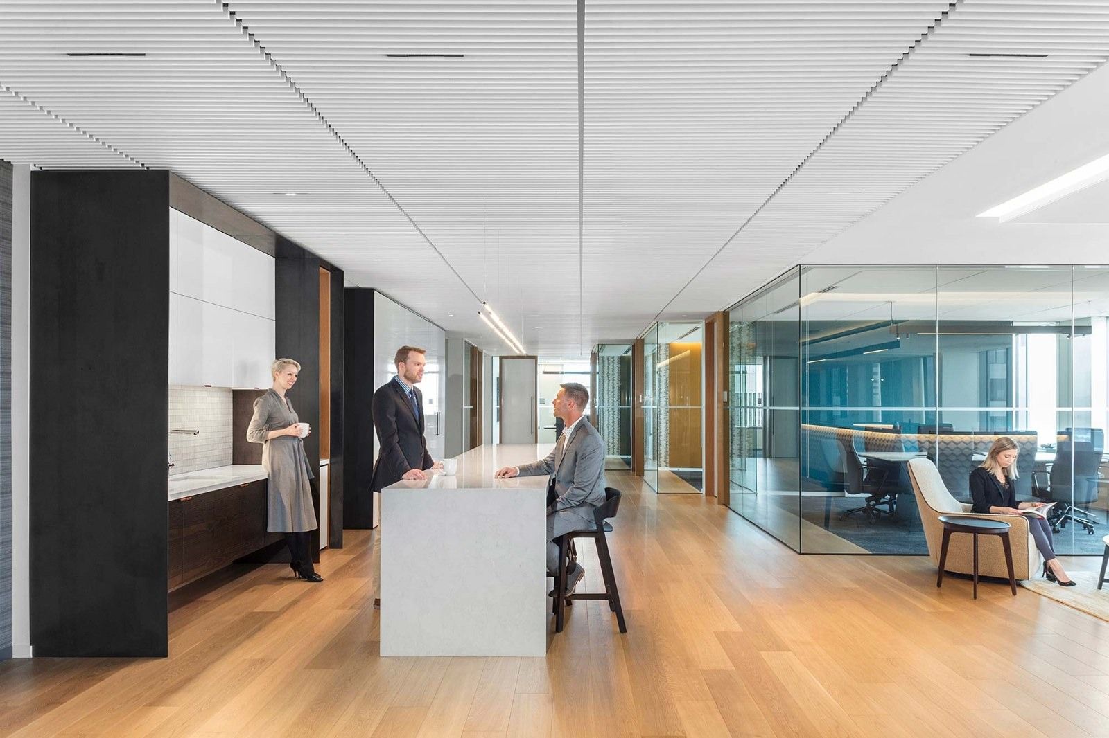 Davis Wright Tremaine: A white counter and stools beside glass meeting rooms