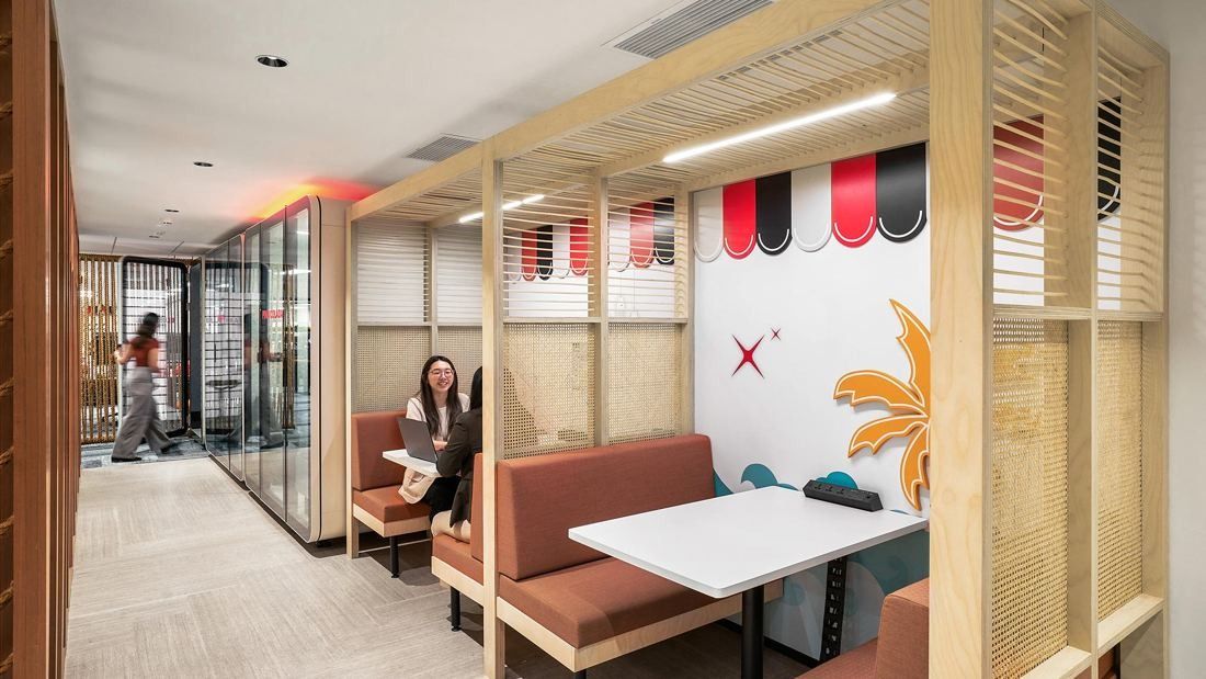 DBS Bank: Booth seating under a timber frame with a striped awning graphic beside a corridor of phone booths