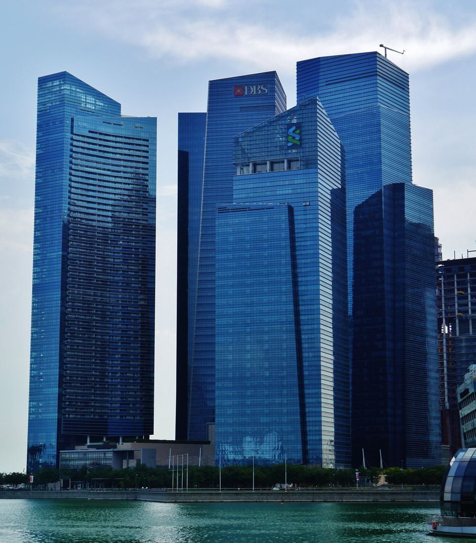 DBS Bank: Cluster of blue glass office towers seen from across the water