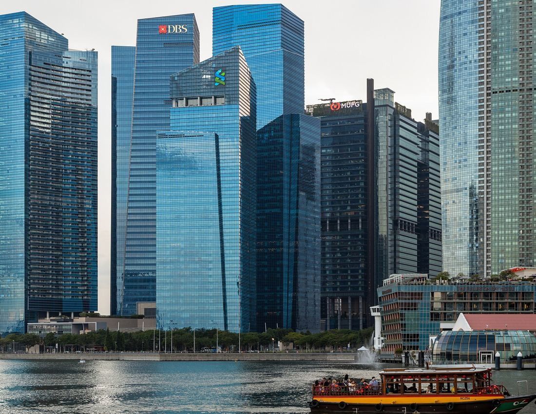DBS Bank: Glass towers along the waterfront with a red tour boat in the foreground