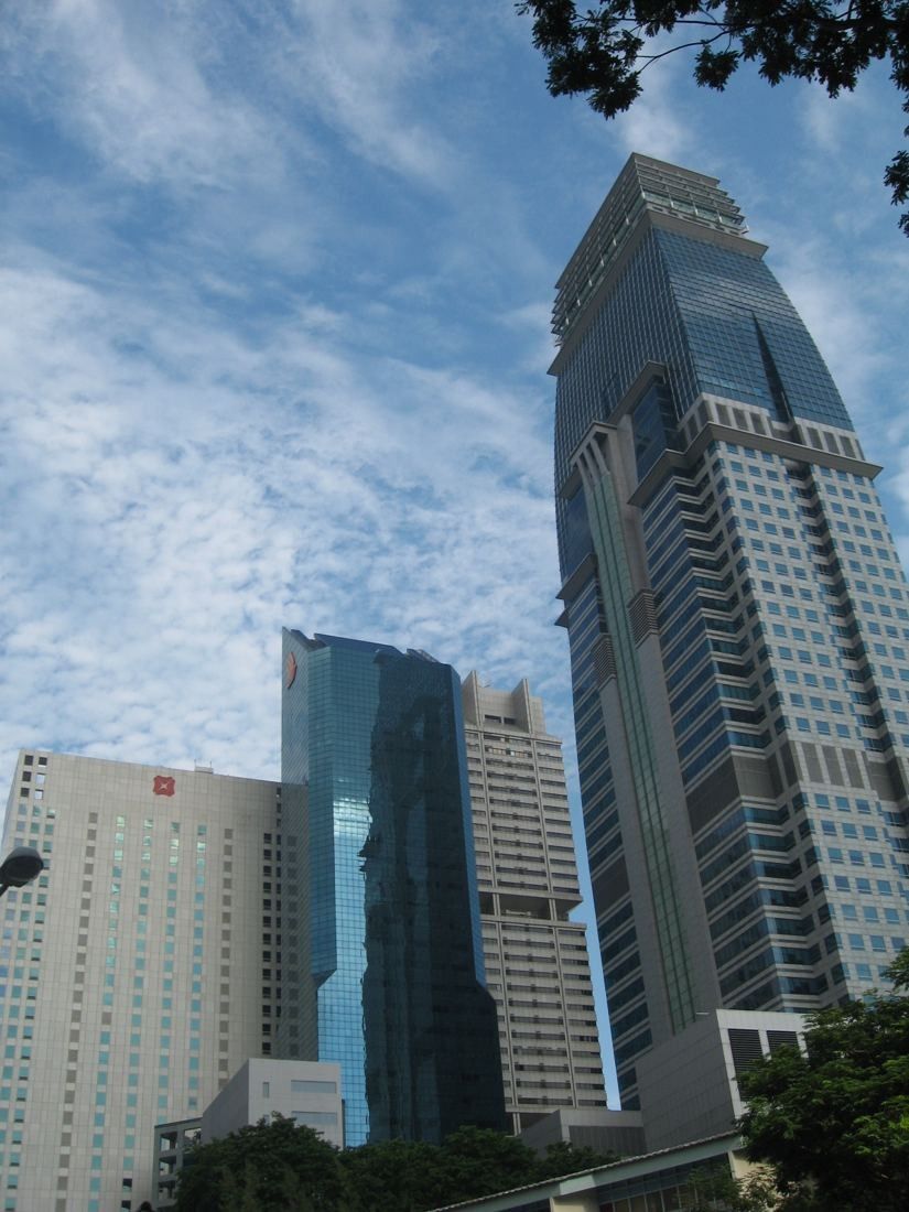 Looking up at tall office towers on Shenton Way against a blue sky