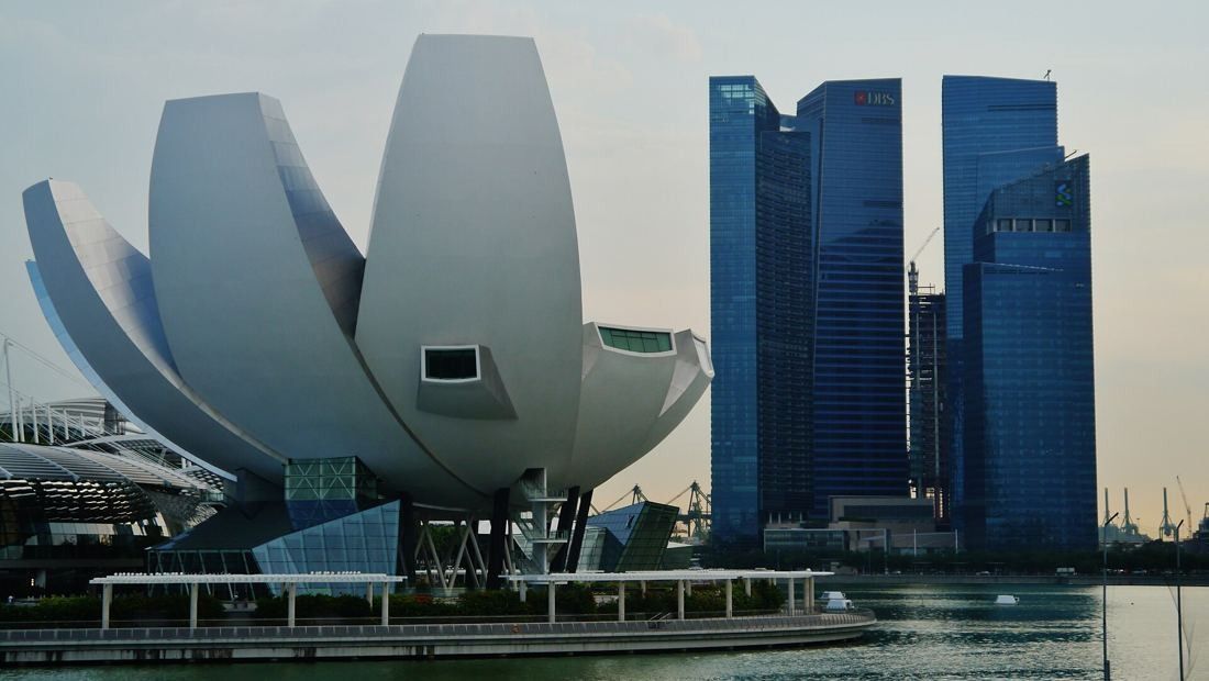 DBS Bank: Lotus-shaped museum building in front of the blue glass Marina Bay Financial Centre towers