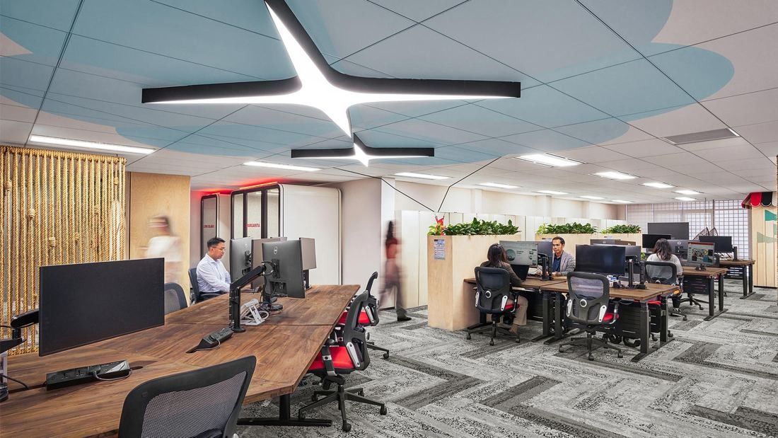 DBS Bank: Open office with wooden desks, red task chairs and a star-shaped light on a blue painted ceiling