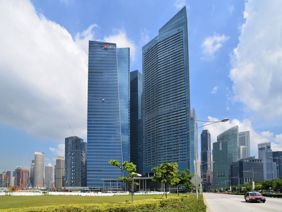 DBS Bank: Two tall glass towers under a blue sky with a lawn and young trees in front