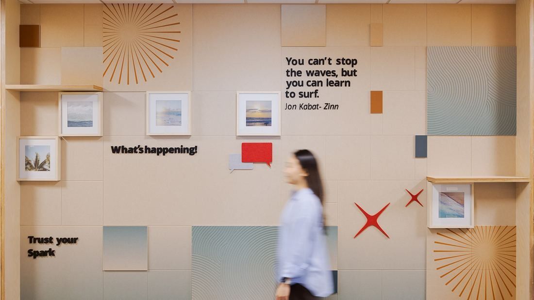 DBS Bank: Wall with framed pictures, sun motifs and short slogans, a person walking past in motion blur