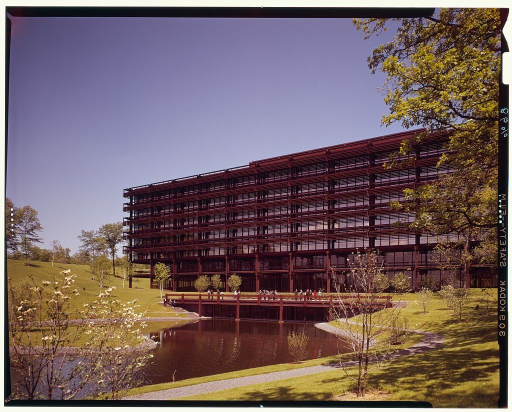 1960s color photo of a steel building beside a pond