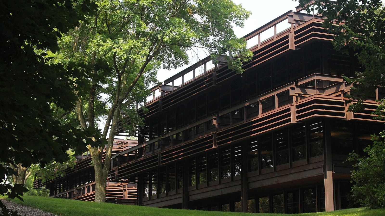 John Deere: Stepped steel building behind trees on a slope