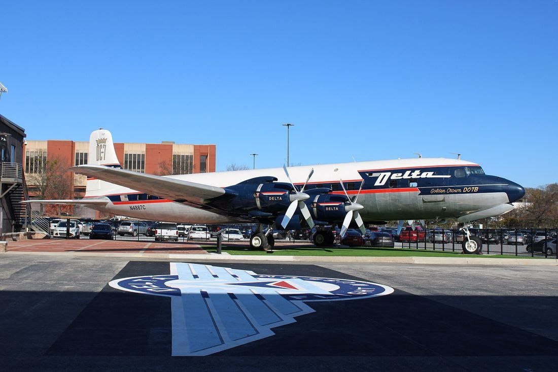 Delta Air Lines: Four-engine propeller airliner in Delta colors parked on an outdoor apron in front of a brick building