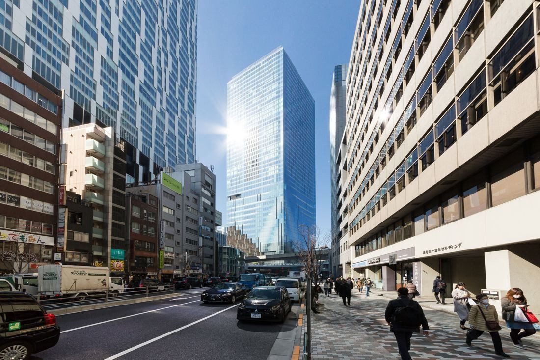 A tall glass tower rising at the end of a city street lined with office buildings