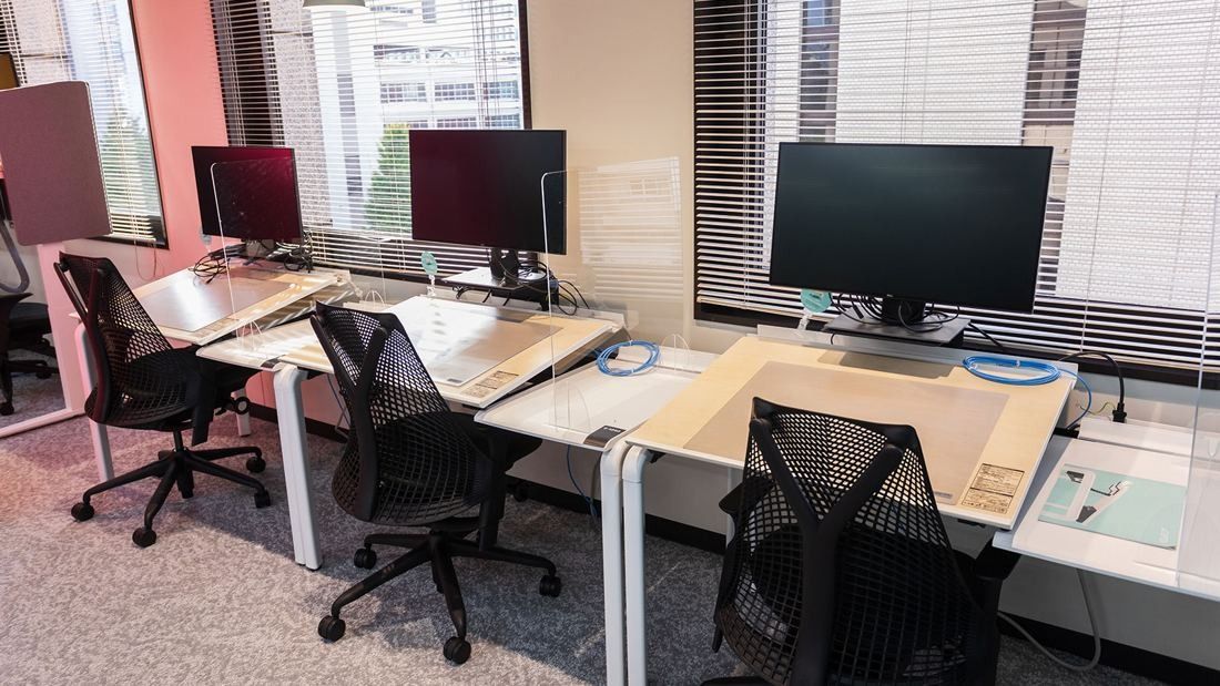 DeNA: Desks with large monitors and mesh chairs by a window