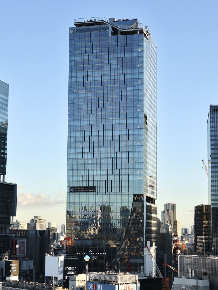 DeNA: Glass skyscraper in evening light above the station area