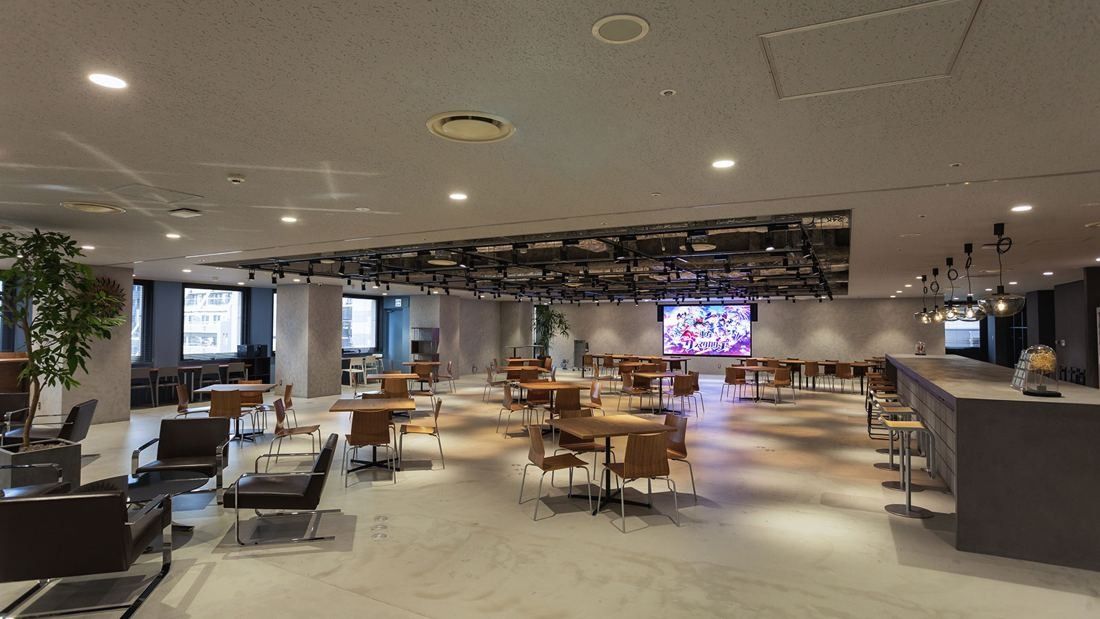 DeNA: Large open lounge area with tables and a screen at the far end