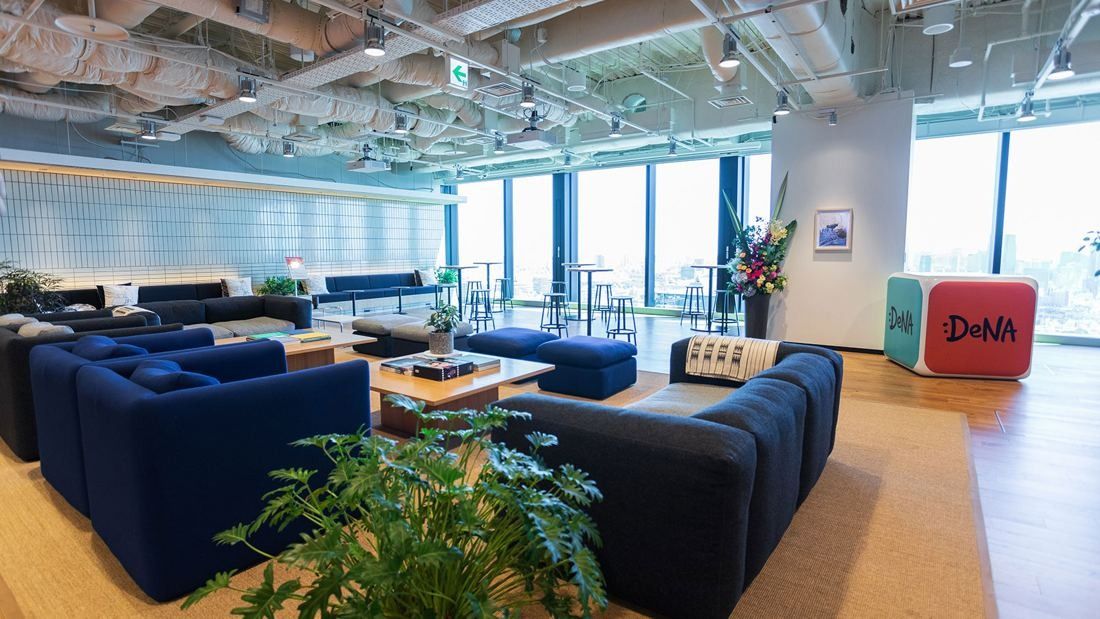 DeNA: Lounge with blue and dark sofas, plants and floor-to-ceiling windows