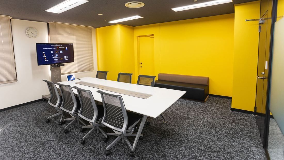 DeNA: Meeting room with a white table and a bright yellow wall