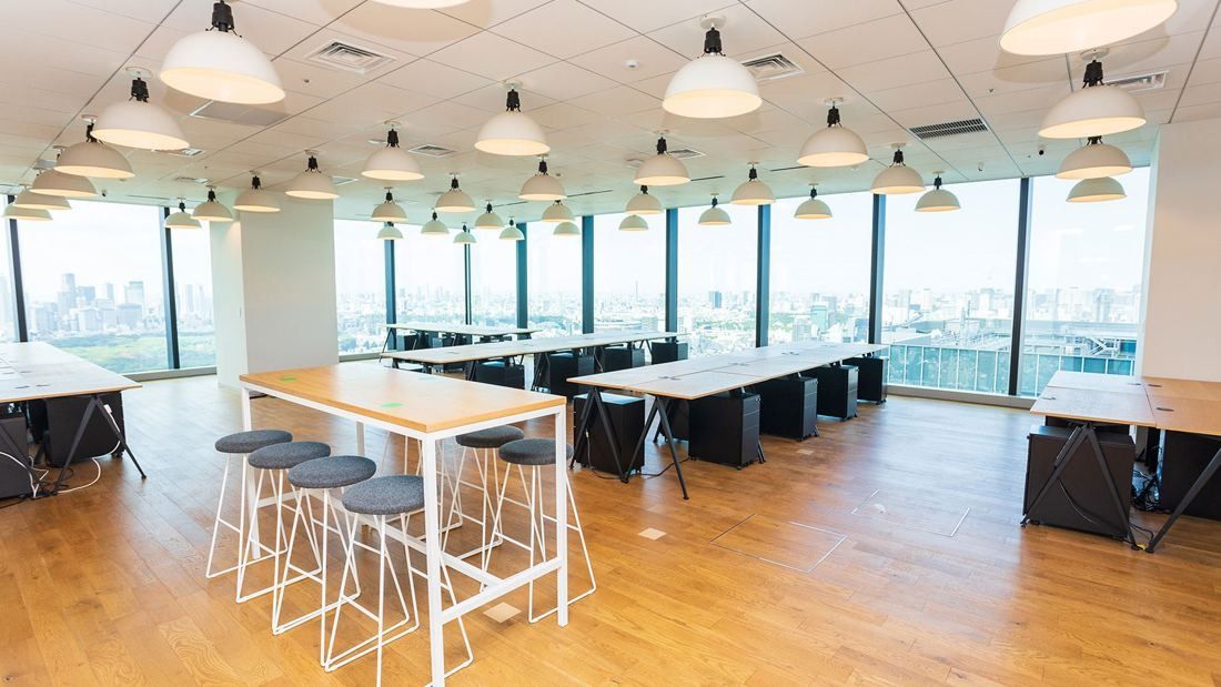 DeNA: Open office area with high bar tables and stools by the windows