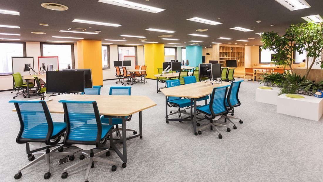 DeNA: Open office with blue chairs, wooden tables and colourful pillars