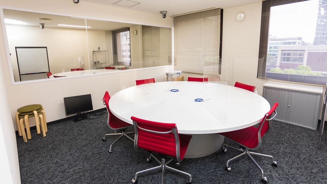 DeNA: Round white table with red chairs in a small room